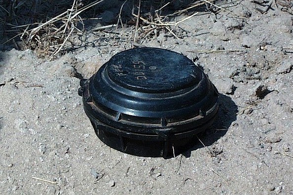 Eine runde Plastikmine im Sand.