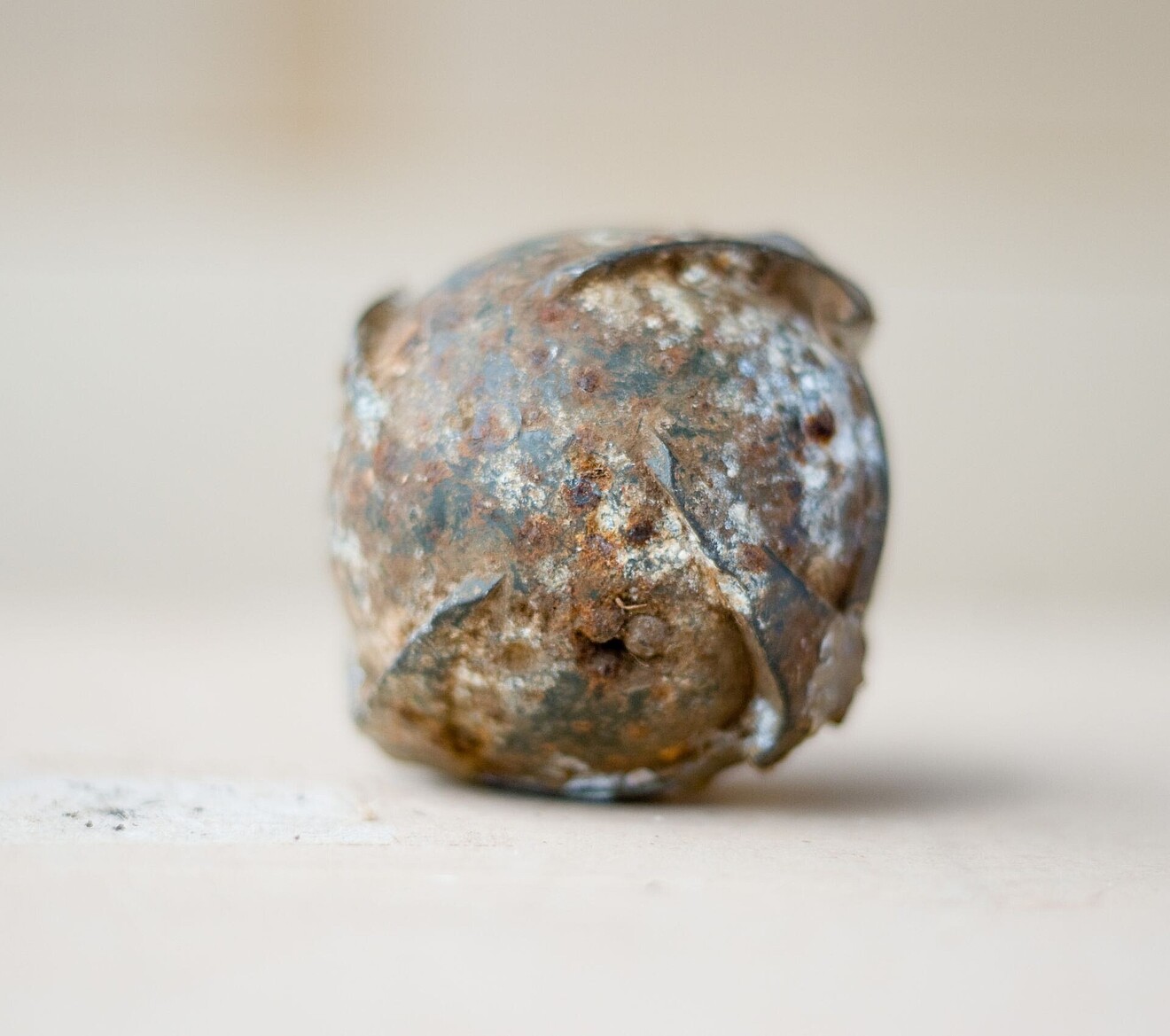 Die Submunition ist ein runder metallischer Ball, schmutzig und rostig.