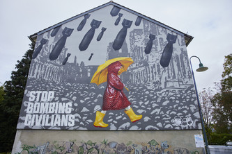 Eine Figur mit Regenklamotten und Regenschirm läuft unter einem bedrohlichen Bombenschauer